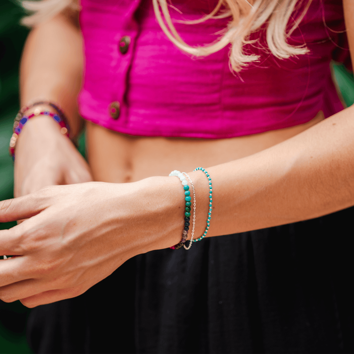 Model wearing a stack of three bracelets. The bracelets include a 4mm multicolor stone healing bracelet, a dainty silver chain bracelet and a 2mm turquoise stone and gold bead healing bracelet
