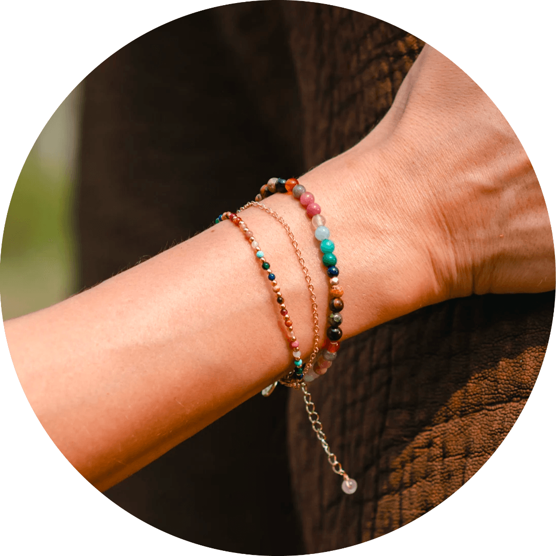 Model wearing a stack of three bracelets. Bracelets include a 4mm multicolor stone bracelet, a 2mm multicolor stone bracelet and a dainty gold chain bracelet