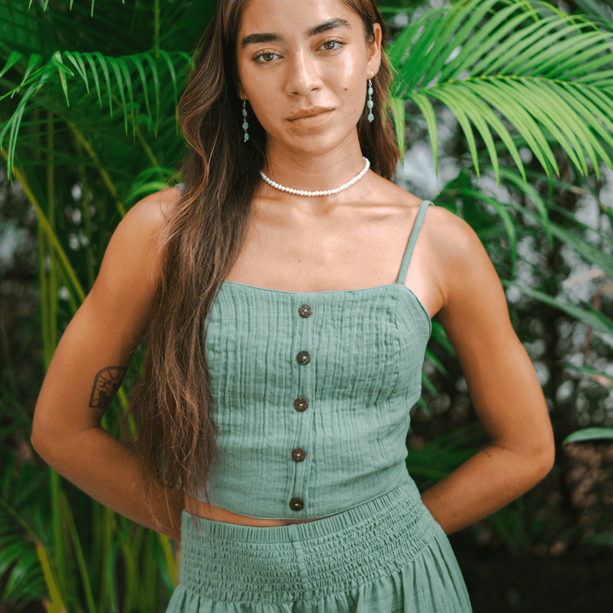 Model wearing sage colored tank top with front button detailing