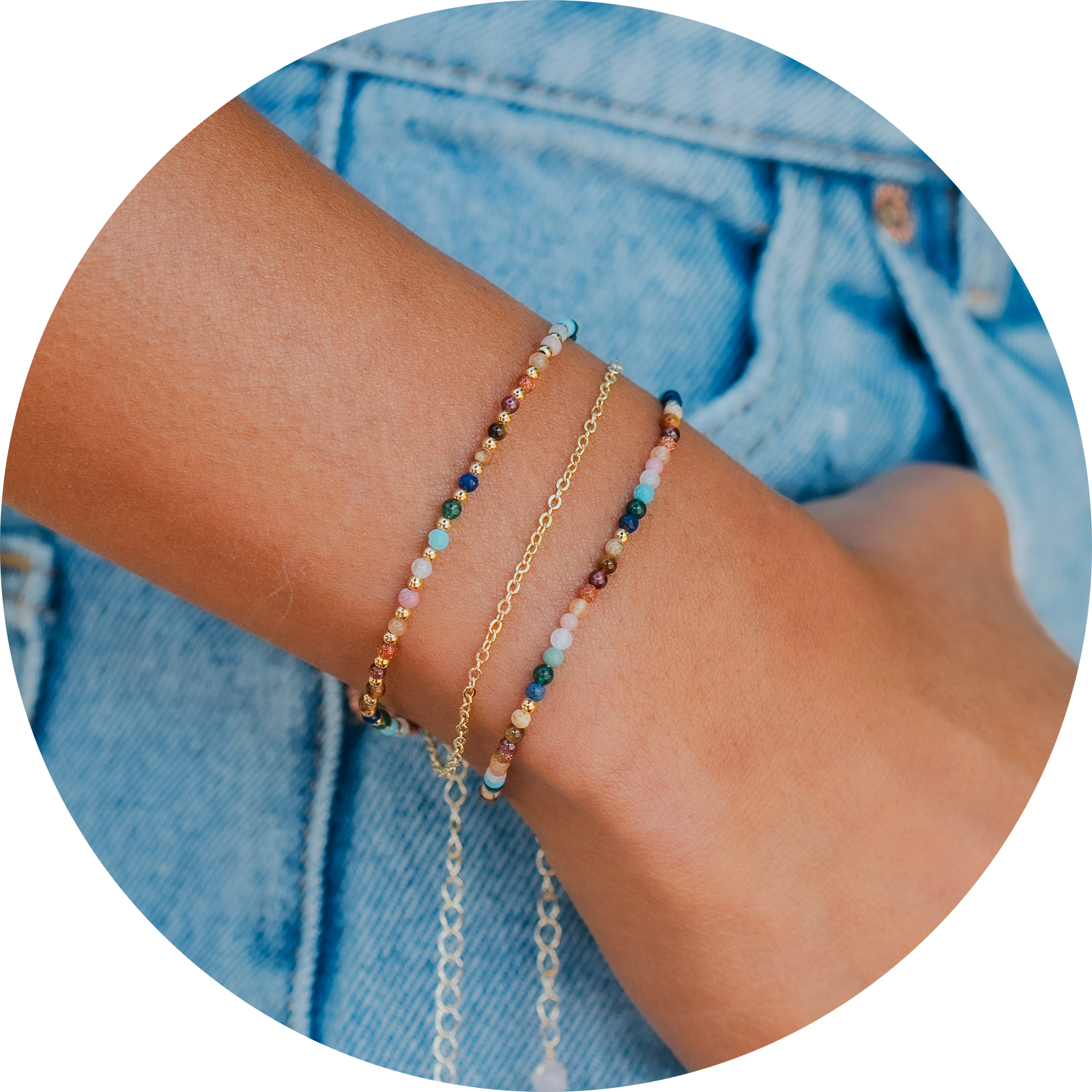 Layered bracelet stack with a rainbow stone and gold bead bracelet, a dainty gold chain bracelet and a rainbow stone bracelet