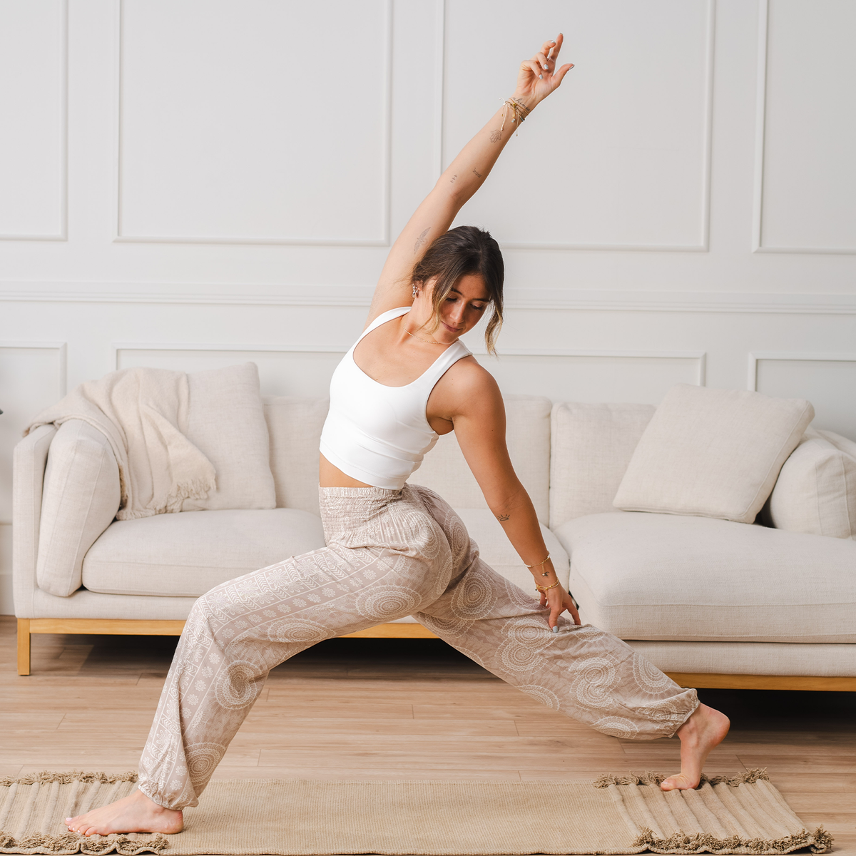Model doing a yoga pose wearing light taupe and white mandala print harem pants