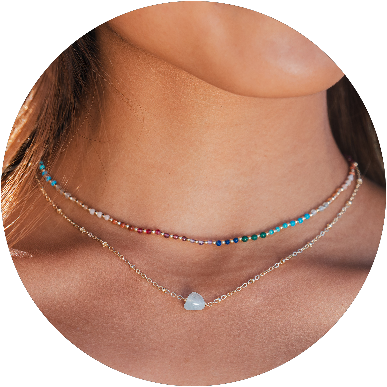Model wearing a healing necklace stack. The necklace include a 2mm multicolor stone and gold bead healing necklace and an aquamarine stone and gold chain necklace