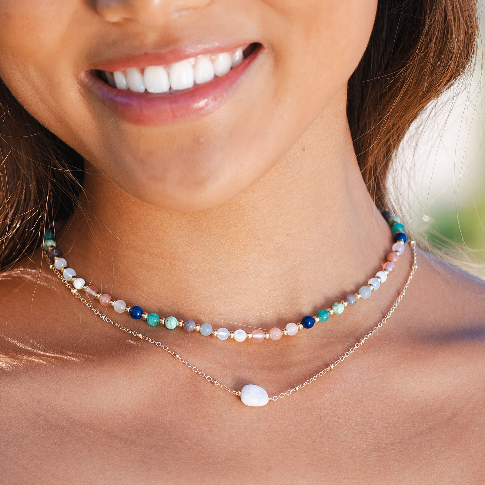 Model wearing a 4mm multicolor stone and gold bead healing necklace and a moonstone healing necklace with a gold chain.