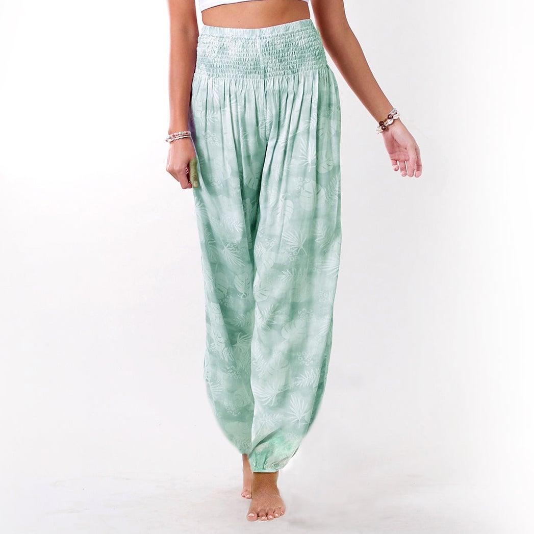 Model wearing light green harem pants with a green palm leaf pattern 