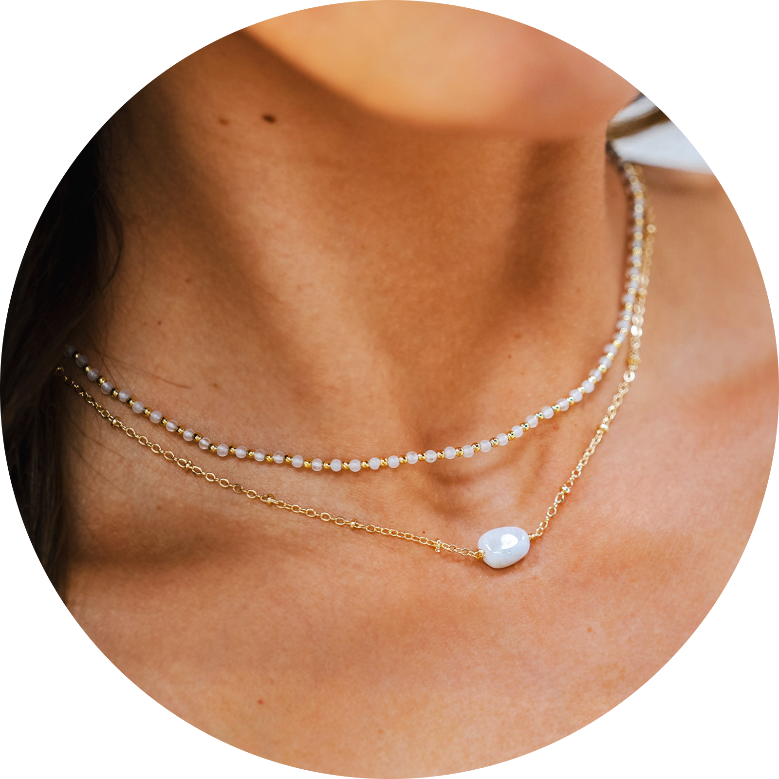 Model wearing a necklace stack. The stack consists of a 2mm moonstone and gold bead healing necklace and a moonstone healing necklace with a gold chain